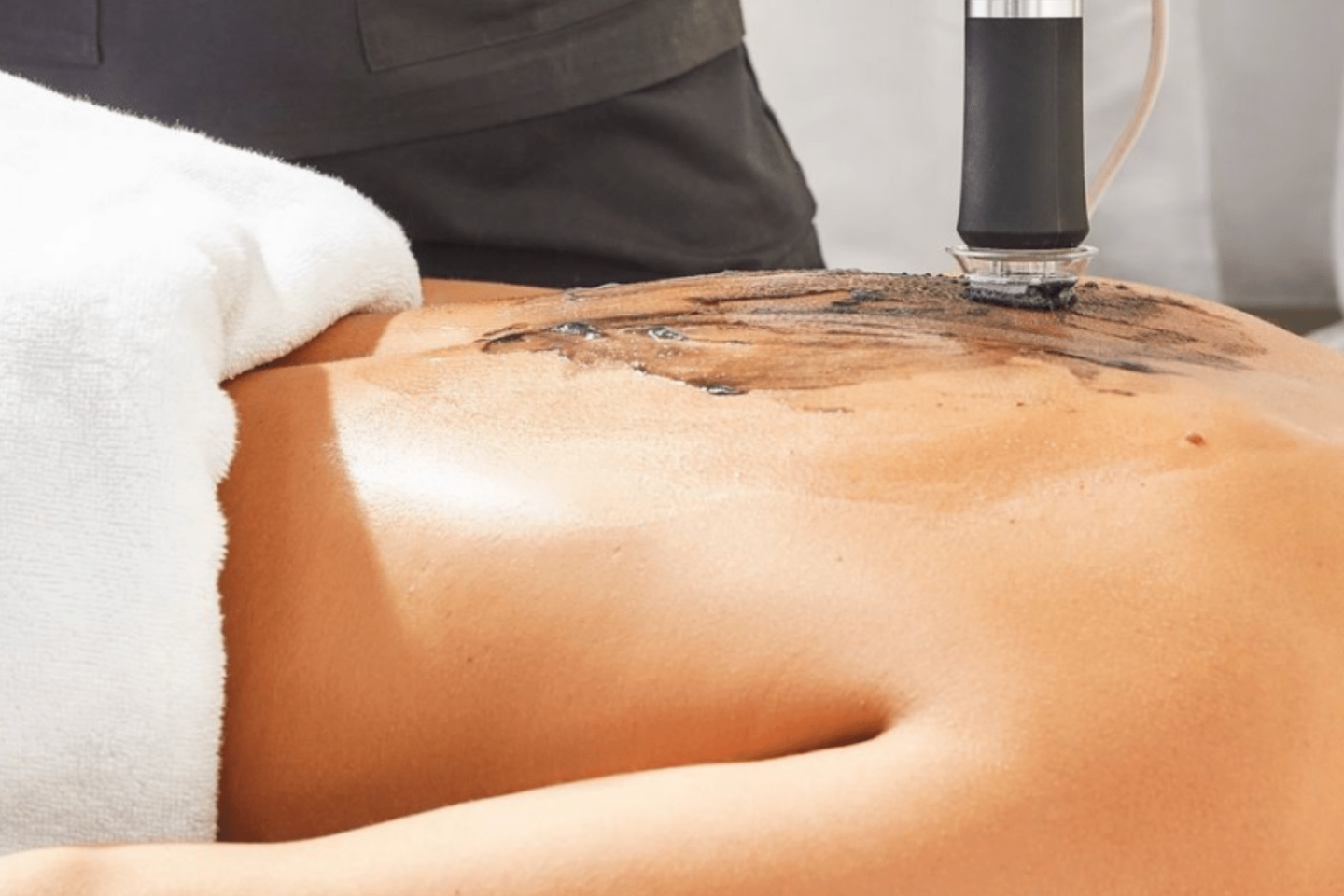Esthetician performing Geneo full body facial treatment on a woman's back.