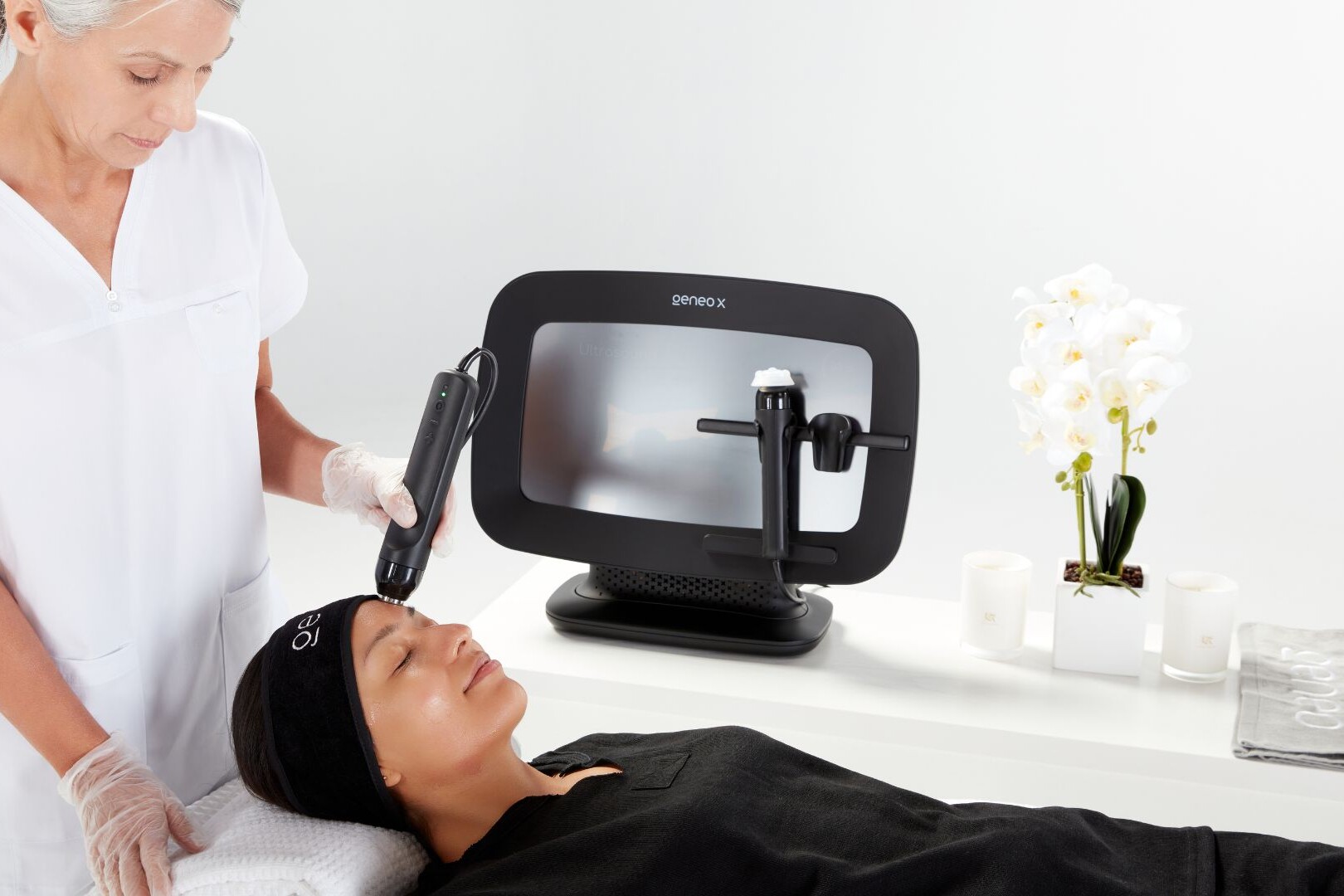 Woman wearing black headband and outfit receiving professional Geneo facial treatment